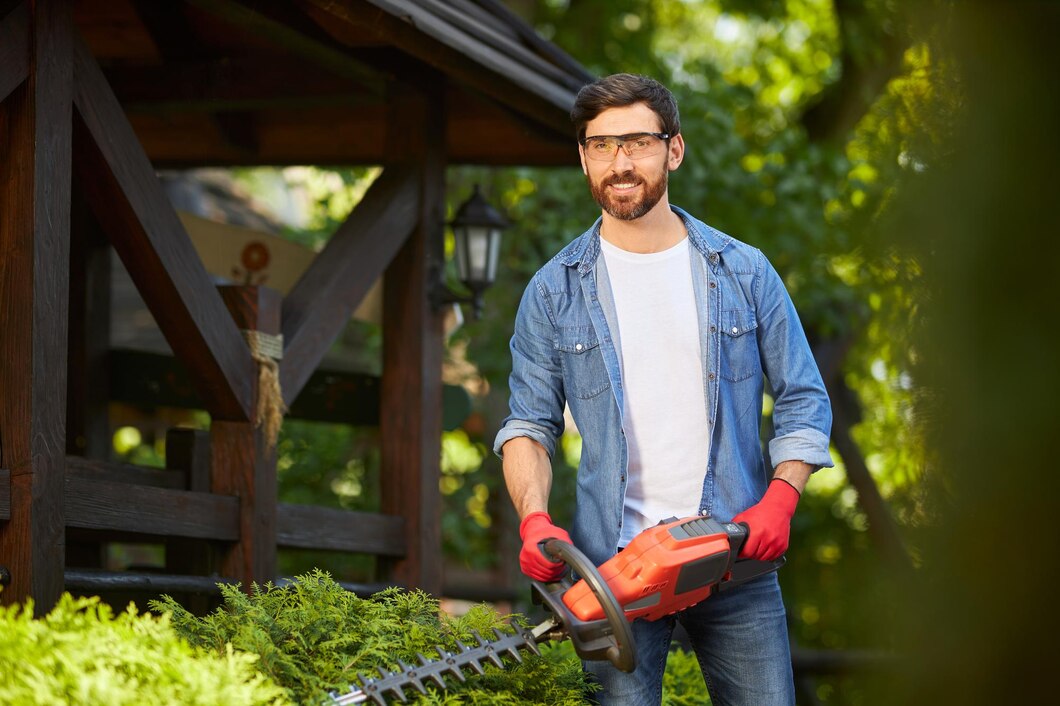 attractive-gardener-posing-while-trimming-conifer-bush-by-electric-hedge-clippers-sunny-day_7502-10442